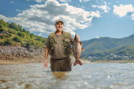 Pescador sosteniendo un pez carpa grande dentro de un lago