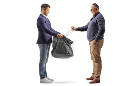 Photo for Full length profile shot of a mature man throwing a plastic bottle in a black waste bag isolated on white background - Royalty Free Image
