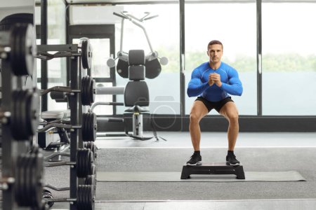 Photo for Young man in sportswear exercising on a stepper at a gym - Royalty Free Image