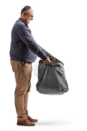 Téléchargez les photos : Mature homme tenant un sac poubelle en plastique noir isolé sur fond blanc - en image libre de droit