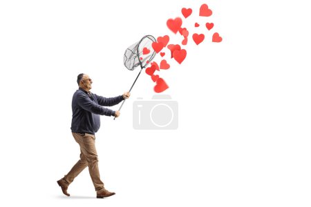 Téléchargez les photos : Homme mûr attrapant des cœurs rouges avec un filet isolé sur fond blanc - en image libre de droit