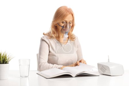 Téléchargez les photos : Femme lisant un livre en utilisant un nébuliseur isolé sur fond blanc - en image libre de droit