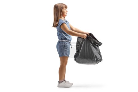 Téléchargez les photos : Petite fille tenant un sac ouvert en plastique noir isolé sur fond blanc - en image libre de droit