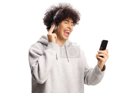 Téléchargez les photos : Jeune homme excité avec casque souriant et écoutant de la musique isolée sur fond blanc - en image libre de droit
