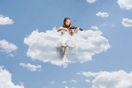 Téléchargez les photos : Fille dans une robe blanche assise sur un nuage et jouant un violon dans le ciel - en image libre de droit