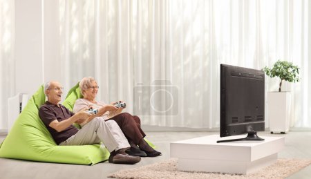 Elderly couple playing video games in front of tv at home