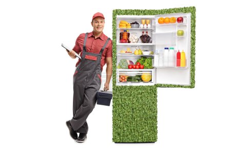 Full length portrait of a repairman with a green eco-friendly fridge isolated on white background