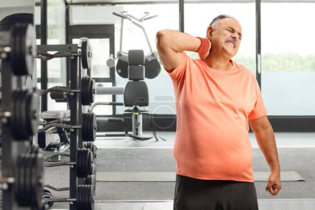 Photo for Corpulent mature man in pain, holding his neck at the gym - Royalty Free Image
