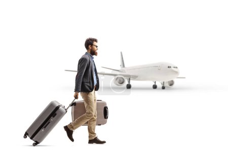 Téléchargez les photos : Photo de profil pleine longueur d'un homme avec des valises marchant vers un avion isolé sur fond blanc - en image libre de droit