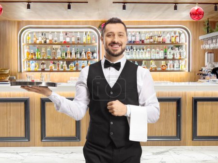Photo for Waiter carrying a silver tray and smiling at a bar - Royalty Free Image