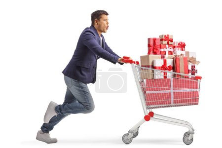 Photo for Excited young man running with presents in a shopping cart  isolated on white background - Royalty Free Image