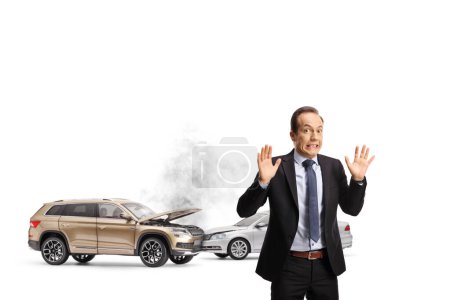 Shocked businessman gesturing with hands in front of a car crash isolted on white background