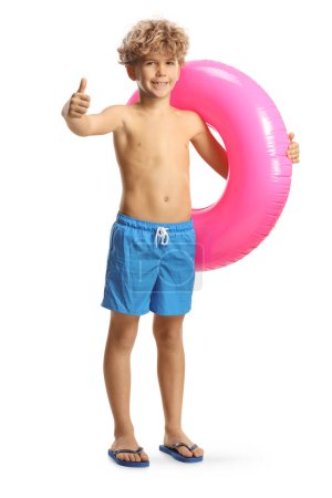 Foto de Niño de pie con un anillo de natación de goma rosa y el gesto pulgares hacia arriba aislado sobre fondo blanco - Imagen libre de derechos