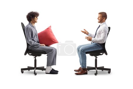 Téléchargez les photos : Plan du profil d'un homme d'affaires assis dans une chaise de bureau et parlant à un homme en pyjama isolé sur fond blanc - en image libre de droit