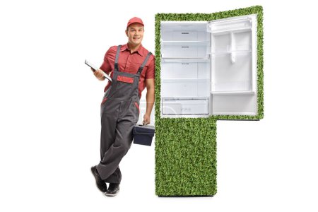 Repairman with a clipboard and a tool box leaning against a green sustainable fridge isolated on white background