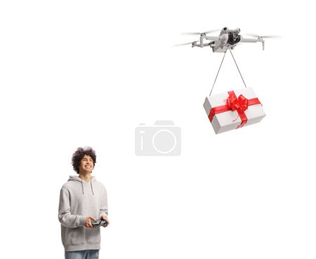 Téléchargez les photos : Joyeux jeune homme livrant une boîte cadeau avec un drone isolé sur fond blanc - en image libre de droit