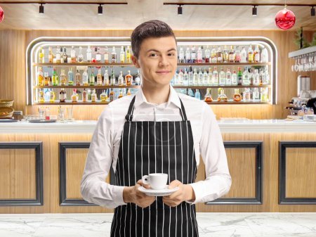 Photo for Young waiter holding espresso coffee cup in front of a bar - Royalty Free Image
