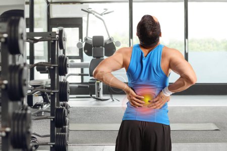 Foto de Vista trasera de un hombre en un gimnasio sosteniendo su dolorosa espalda - Imagen libre de derechos