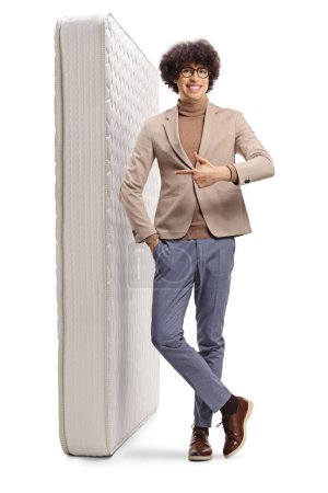 Photo for Young man pointing at a mattress isolated on white background - Royalty Free Image