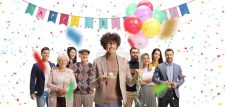 Photo for Young man with a birthday cupcake and a bunch of balloons celebrating with people isolated on white background - Royalty Free Image