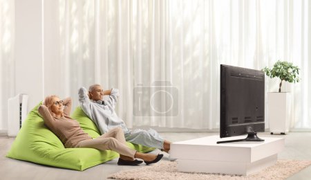 Photo for Caucasian woman and african american guy sitting on beanbags in front of tv at home - Royalty Free Image