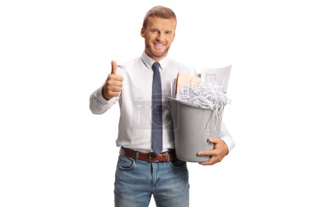 Photo for Office worker holding a bin with paper waste and gesturing thumbs up isolated on white background - Royalty Free Image