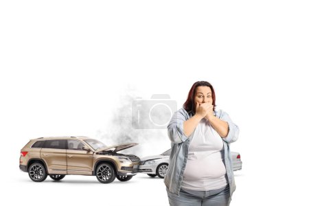 Foto de Accidente de coche y una mujer impactada cubriendo la boca con las manos aisladas sobre fondo azul - Imagen libre de derechos