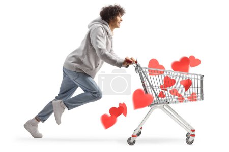 Photo for Young man running with hearts in a shopping cart isolated on white background - Royalty Free Image