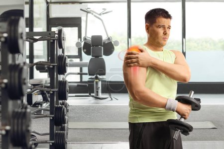 Foto de Hombre con lesión en el hombro y área inflamada roja levantando pesas en un gimnasio - Imagen libre de derechos