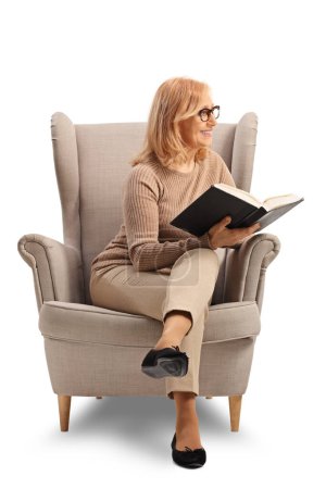 Téléchargez les photos : Femme assise dans un fauteuil avec un livre ouvert isolé sur fond blanc - en image libre de droit