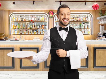 Foto de Camarero profesional sosteniendo un plato y sonriendo en un restaurante bar - Imagen libre de derechos