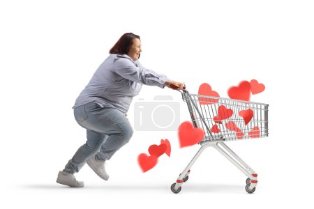 Foto de Perfil de una mujer corpulenta corriendo y empujando un carrito de compras con corazones aislados sobre fondo blanco - Imagen libre de derechos