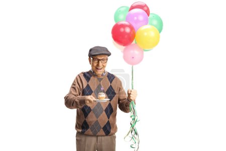 Foto de Anciano soplando una vela en una magdalena de cumpleaños y sosteniendo globos aislados sobre fondo blanco - Imagen libre de derechos
