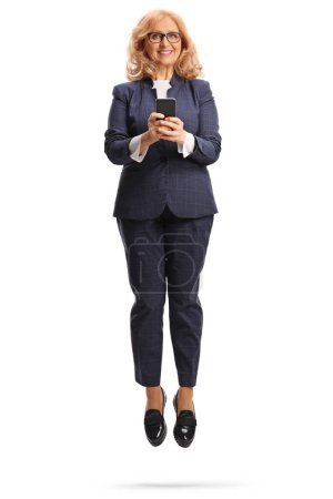 Happy middle aged businesswoman using a smartphone and jumping isolated on white background