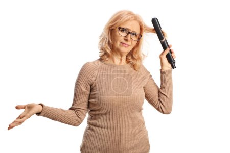 Téléchargez les photos : Femme confondue utilisant un lisseur de cheveux isolé sur fond blanc - en image libre de droit