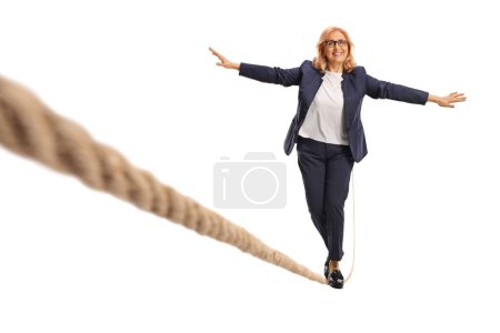 Photo for Full length portrait of a middle aged woman walking on a rope isolated on white background - Royalty Free Image