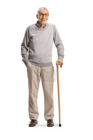 Téléchargez les photos : Homme âgé debout avec une canne et souriant isolé sur fond blanc - en image libre de droit