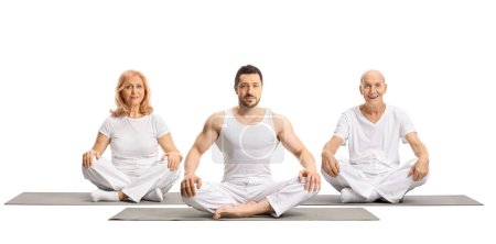 Photo for Male yoga instructor on a mat with elderly man and mature woman sitting behind isolated on white background - Royalty Free Image