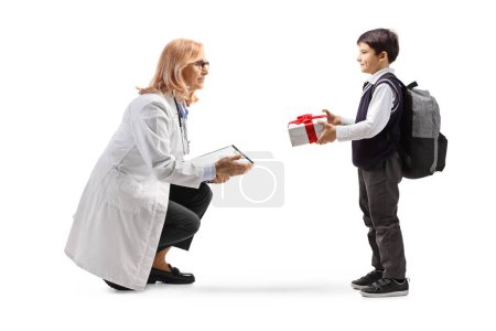 Foto de Niño dando un regalo a una doctora aislada sobre fondo blanco - Imagen libre de derechos
