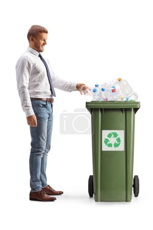 Téléchargez les photos : Photo de profil pleine longueur d'un homme jetant une bouteille en plastique dans une poubelle isolée sur fond blanc - en image libre de droit