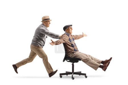 Foto de Anciano corriendo y empujando a un amigo en una silla de oficina aislado sobre fondo blanco - Imagen libre de derechos