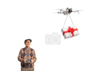 Photo for Elderly man flying a drone with a remote controller and delivering a present isolated on white background - Royalty Free Image