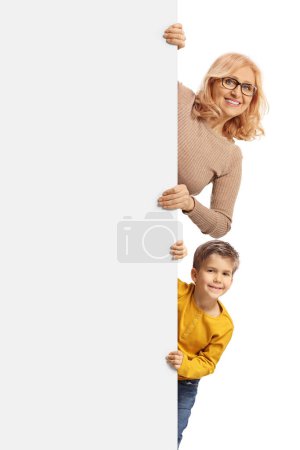 Photo for Mother and boy behind white panel smiling at camera isolated on white background - Royalty Free Image
