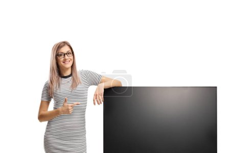 Photo for Young woman pointing at a blank tv screen isolated on white background - Royalty Free Image