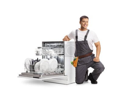 Photo for Repairman kneeling next to a dish washer and smiling isolated on white background - Royalty Free Image