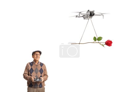 Téléchargez les photos : Homme âgé pilotant un drone avec télécommande et délivrant une rose rouge isolée sur fond blanc - en image libre de droit