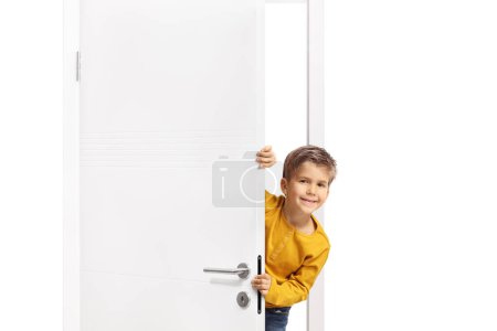 Téléchargez les photos : Mignon petit garçon caché derrière une porte - en image libre de droit