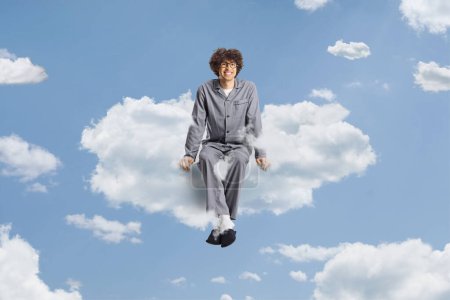 Photo for Young man in pajamas and slippers floating on a cloud - Royalty Free Image