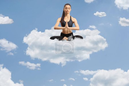 Photo for Young female practicing meditation on a cloud up in the sky - Royalty Free Image