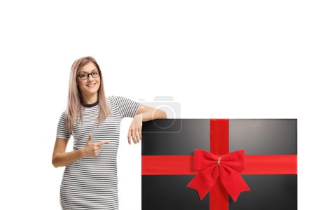 Photo for Young woman pointing at a tv flat hd screen tied with a red ribbon isolated on white background - Royalty Free Image